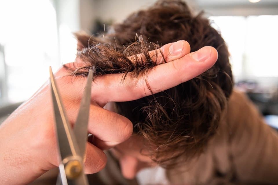 Stylist cutting a man's hair with scissors